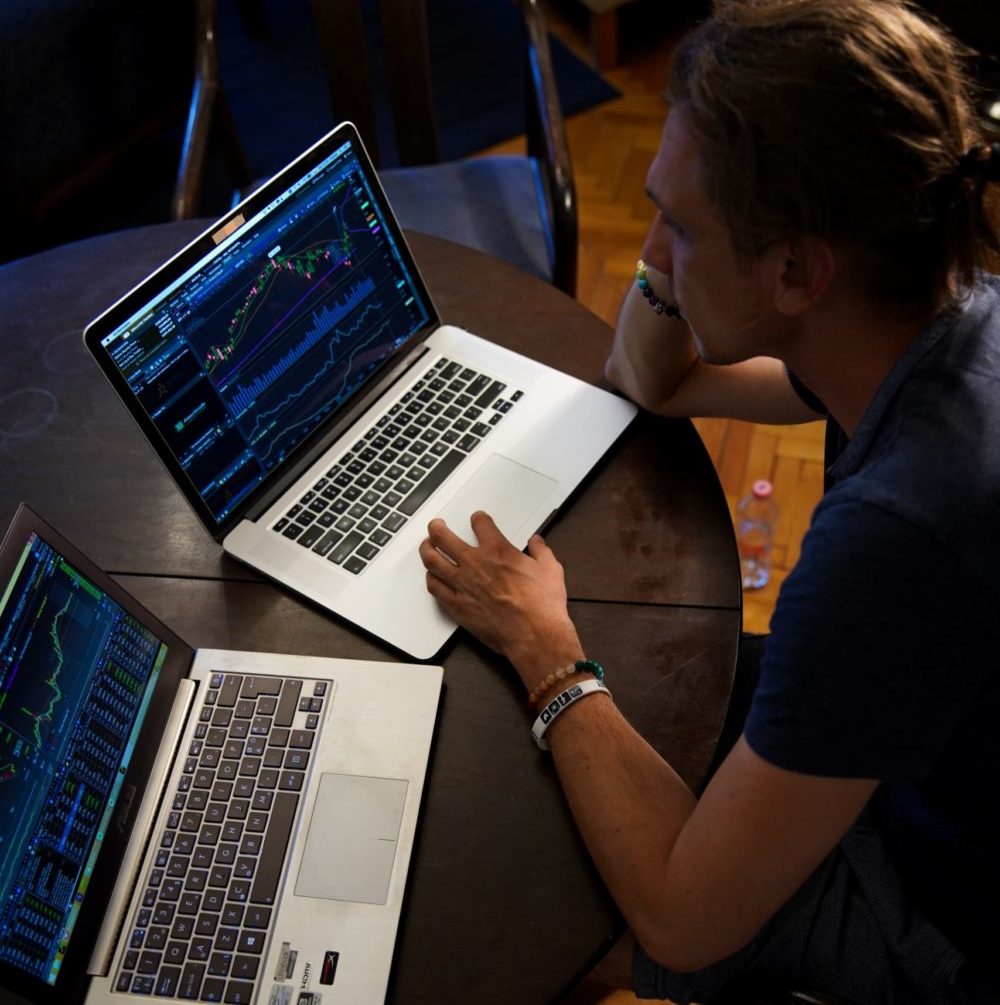 A woman working at two laptops.