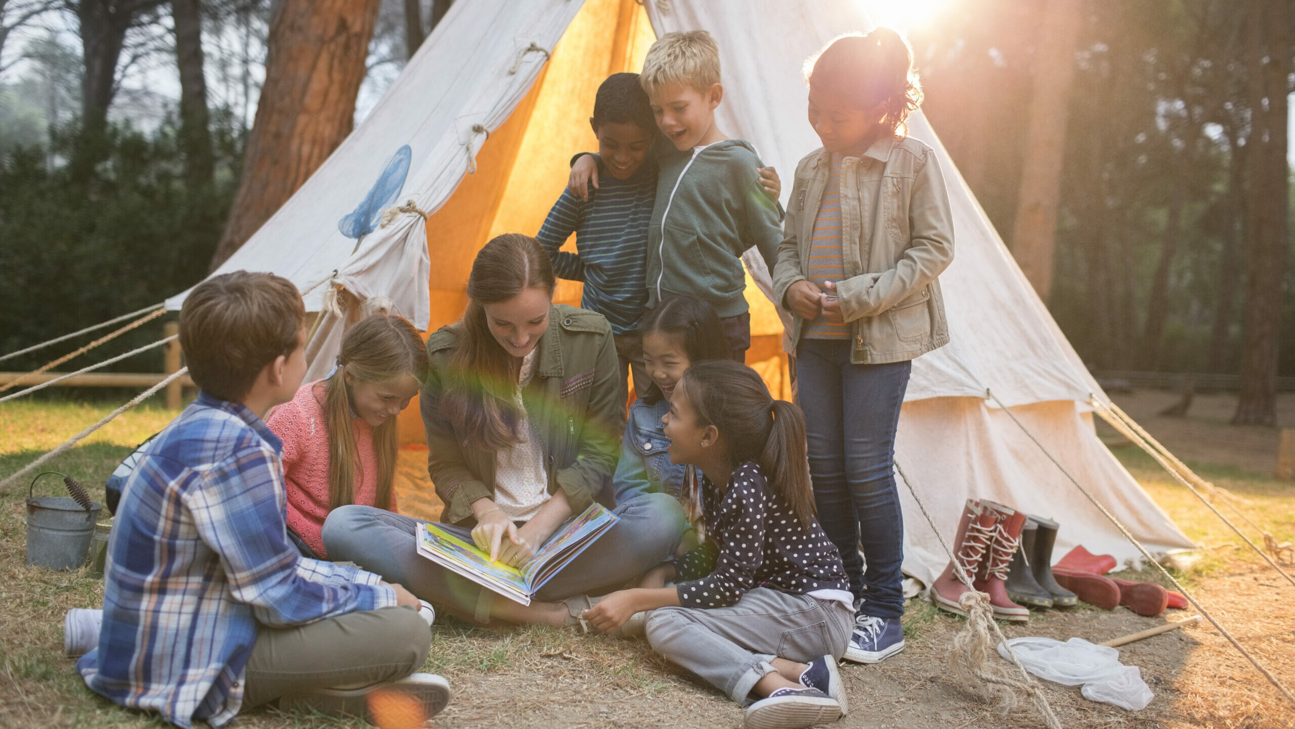 Teacher and students reading at campsite